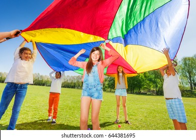 Kids Playing With Rainbow Parachute In The Park