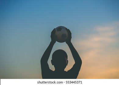 Kids Are Playing Soccer Football For Exercise Under The Sunlight. Silhouette And Film Picture Style.