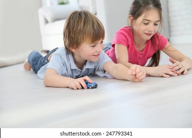 Kids Playing With Toy Cars Laying On Floor