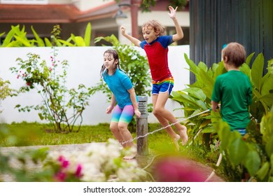 Kids Playing With Water Hose In Summer Garden. Child Water Sprinkler Fun On Hot Sunny Day. Children Jump And Run In The Backyard. Brother And Sister Play Outside. Healthy Outdoor Activity For Child.