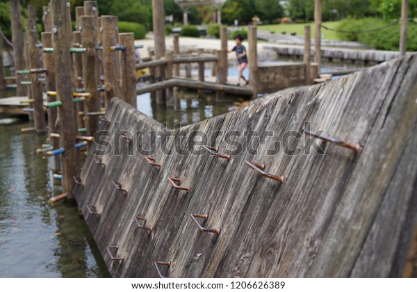 Kids playing with wooden playground equipment\
by waterside