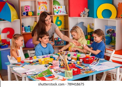 Kids playroom organization of children painting and drawing in kid's club. Craft lesson in primary school. Teaching children to do common project.