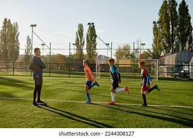 Kids practicing soccer on grass field under football coach control - Powered by Shutterstock