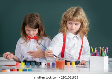 Kids Pupils Learning Painting. School Children Girl And Boy Painting With Paints Color And Brush In Classroom.