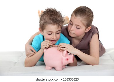 Kids Putting Coins In A Piggy Bank