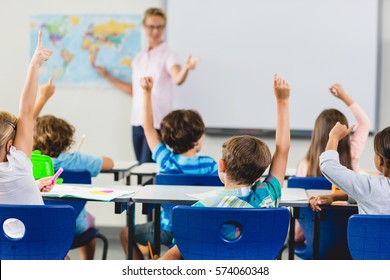 Kids Raising Hand In Classroom At School