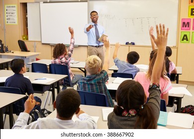 Kids raising hands to answer in an elementary school class