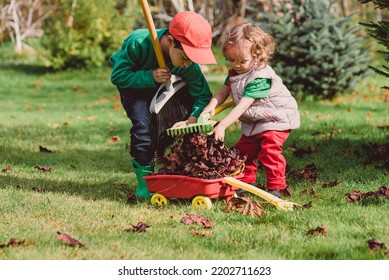 Kids Raking Autumn Leaves Into Wheelbarrow Cleaning Garden Before Winter