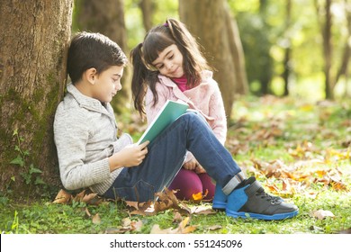 Kids Reading A Book Outdoors