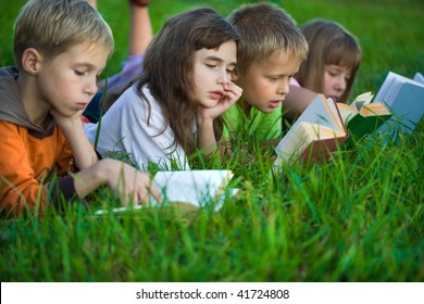Kids are reading books on the green grass