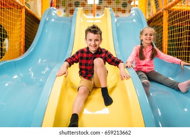 Kids Riding From Childrens Slides In Game Center