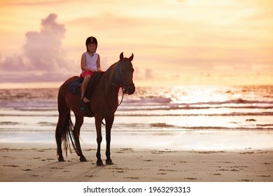 Kids Riding Horse On Beach. Children Ride Horses. Cute Little Girl On Pony On A Ranch. Child And Animal. Kid In Safe Helmet For Horseback Class. Travel With Young Child. Vacation On Ocean Shore. 