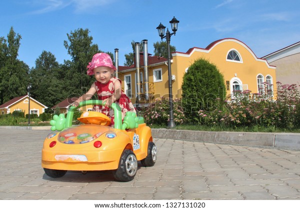 Kids riding Toy Car. Little Girl Riding Car In\
Amusement Park Outdoor. cute little girl enjoy ride on her yellow\
electric car. Baby girl riding on small car. Kid leisure on summer\
day. bucket hat