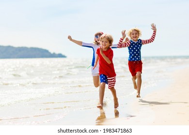 Kids run with USA flag on sunny beach. 4th of July celebration. American family fun on Independence Day weekend. Patriotic children celebrate US holiday. Boy and girl with symbols of America.