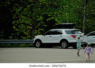 Kids Running To Car In Parking At Austrian Alps.