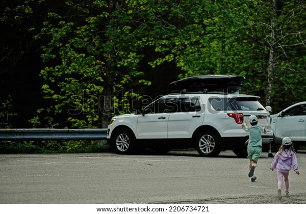 Kids running\
to car in parking at Austrian\
alps.
