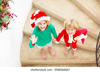 Kids Running Stairs On Christmas Morning. Children In Pajamas Run Downstairs Eager To Open Xmas Presents. Celebration At Home. Winter Family Holiday. Boy And Girl Opening Gifts.