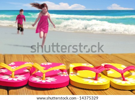 Kids running towards colorful flip flop sandals on boardwalk with ocean in distance