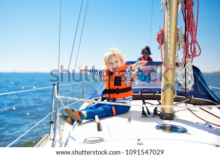 Kids sail on yacht in sea. Child sailing on boat. Little boy in safe life jacket travel on ocean ship. Children enjoy yachting cruise. Summer vacation for family. Young sailor on sailboat front deck.