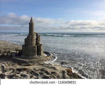 Kids Sand Castle Moat Protects Against Ocean Waves On A Sunny Beach With Blue Skies During Vacation