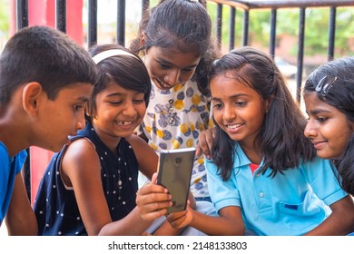 Kids At School Busy Using Mobile Phone While Sitting At Corridor During Break - Concept Of Technology, Smartphone Addiction And Using Social Media