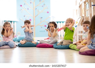 Kids seating on floor and show gestures making task in daycare - Shutterstock ID 1415207417