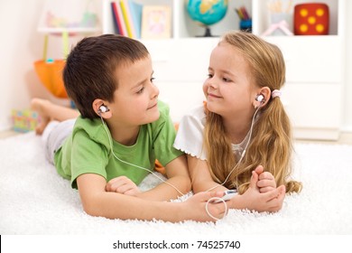 Kids sharing earphones listening to music laying on the floor - Powered by Shutterstock