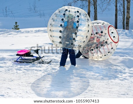 Kids shoving each other in a semi-transparent zorbing. 