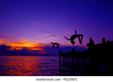 Kids In Silhouette Doing Back-flip Jump To The Water