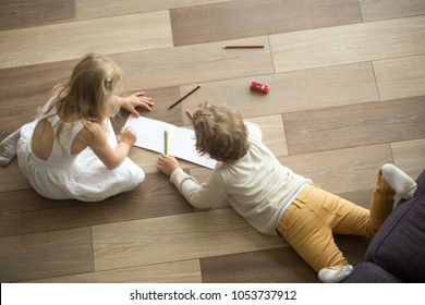 Kids sister and brother playing drawing together on wooden warm floor in living room, creative children boy and girl having fun at home, siblings friendship, underfloor heating concept, top view - Shutterstock ID 1053737912