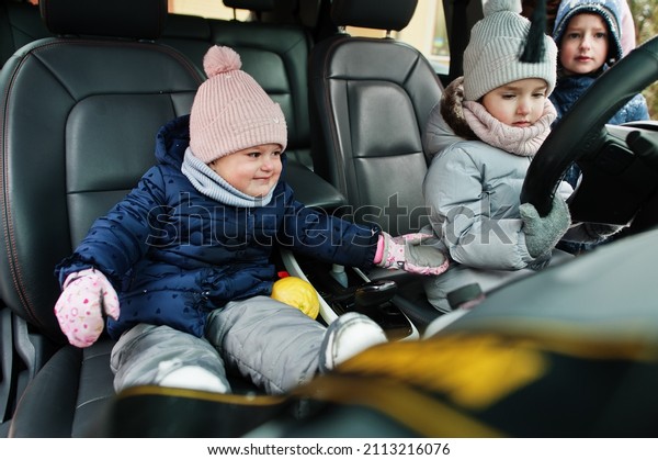 Kids\
sit in electric car in the yard of house at\
winter.