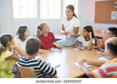 Kids sitting around desk in classroom and studying during lesson. Teacher explaining subject to pupils. - Powered by Shutterstock