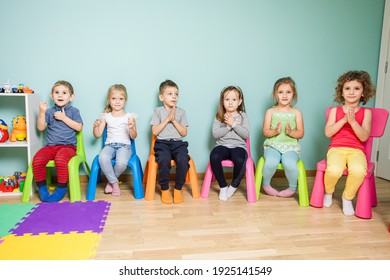 Kids are sitting on the colorful chairs, clapping hand