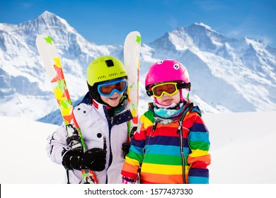 Kids skiing in mountains. Active children with safety helmet, goggles and poles. Ski race for young kids. Winter sport for family. Child ski lesson in alpine school. Little skier racing in snow