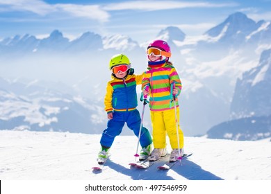 Kids Skiing In Mountains. Active Children With Safety Helmet, Goggles And Poles. Ski Race For Young Kids. Winter Sport For Family. Child Ski Lesson In Alpine School. Little Skier Racing In Snow