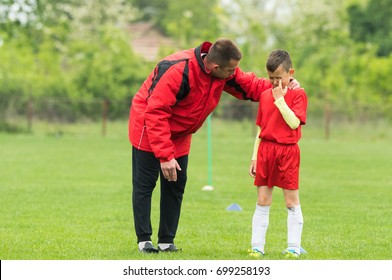 Kids soccer football - coach comfort little soccer player who is crying after a missed goal