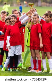 Kids Soccer Football - Young Children Players Celebrating With A Trophy After Match On Soccer Field 