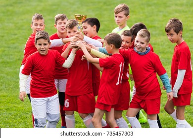 Kids Soccer Football - Young Children Players Celebrating With A Trophy After Match On Soccer Field 