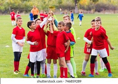 Kids Soccer Football - Young Children Players Celebrating With A Trophy After Match On Soccer Field