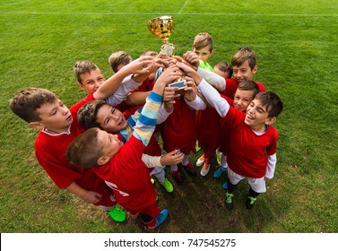 Kids Soccer Football - Young Children Players Celebrating With A Trophy After Match On Soccer Field