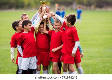 Kids soccer football - young children players celebrating with a trophy after match on soccer field - Powered by Shutterstock