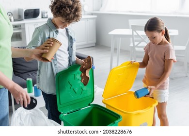 Kids Sorting Garbage Near Mother And Trash Cans With Recycle Sign At Home