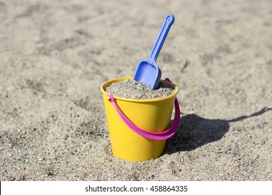 A kids spade put in the bucket in the sand - Powered by Shutterstock