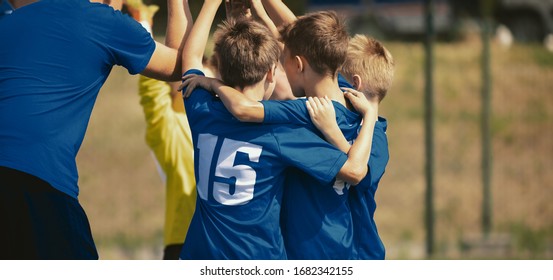 Kids Sport Team Gathering And Rising Hands. Children Play Sports. Boys In Sportswear Jersey Uniforms Having Shout Team. Youth Sports For Children. Youth Football Academy Background With Copy Space 