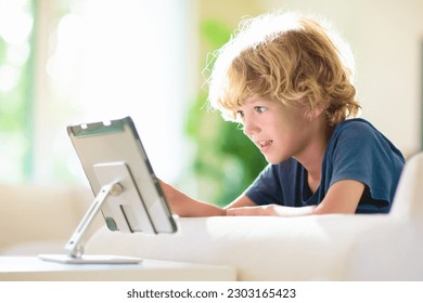 Kids with tablet computer. Child with pc watching movie or playing game. Educational online program for school child. Boy with digital device and gadget. Screen time and education for young kid.  - Powered by Shutterstock