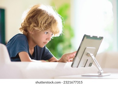Kids with tablet computer. Child with pc watching movie or playing game. Educational online program for school child. Boy with digital device and gadget. Screen time and education for young kid.  - Powered by Shutterstock