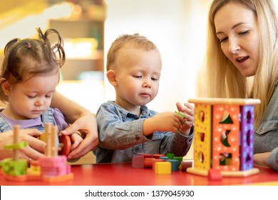 Kids with teacher play with shapes and colorful wooden puzzle in a montessori classroom