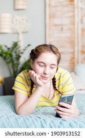 Kids, technology and communication concept-smiling girl reading sms to smartphone and lay in bed at home