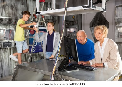 Kids And Their Grandarents Trying To Solve Conundrums In Escape Room By Using Computer And Stepladder.