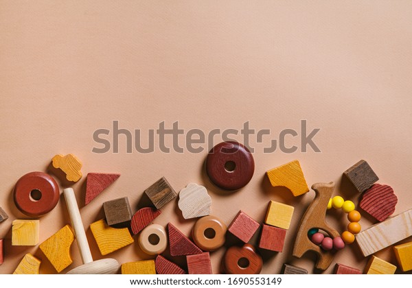Kids toys.\
Wooden cubes, cars, pyramid tower and teether on a peach\
background. Flat lay, top view, copy\
space.